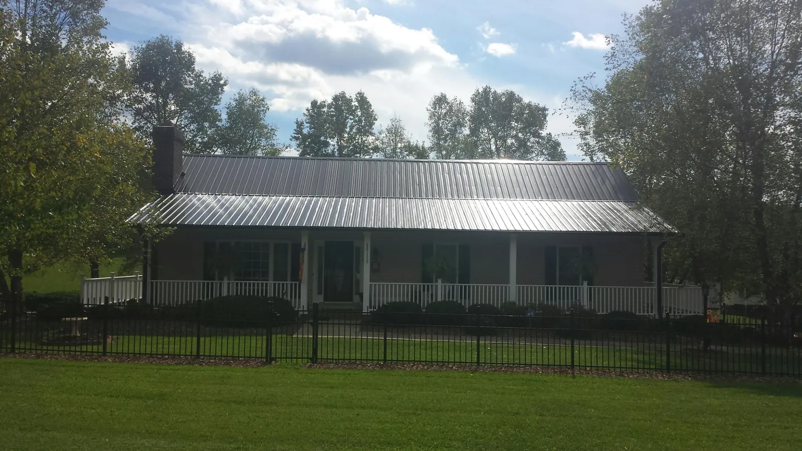 Gray metal roof on a brick ranch with a full width front porch — Gutter Guard Installation work by our crew in Westfall