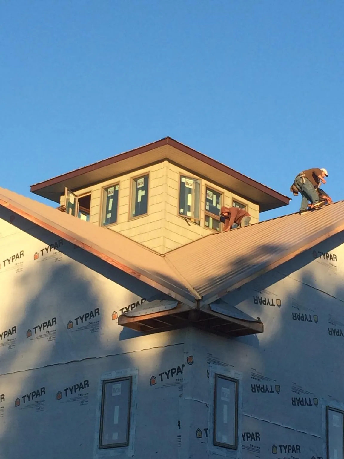 Roofers working around a rooftop cupola on a new metal roof at sunset — Roof Waterproofing in Westfall by Roofing Brothers